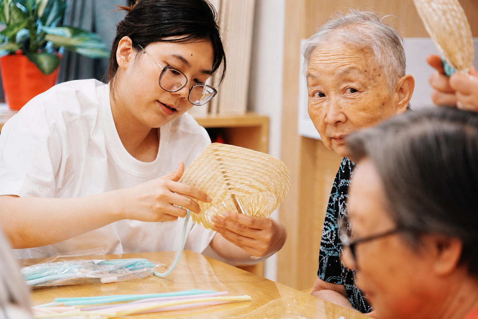 A facilitator supporting an older participant while decorating a hand fan